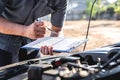 Technician engineer working of car mechanic in doing checklist for repairs engine writing to the clipboard repairing vehicle, Royalty Free Stock Photo