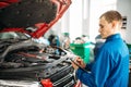 Technician fills check list, car with opened hood Royalty Free Stock Photo