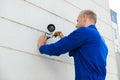 Technician Fixing Camera On Wall