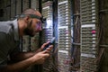 A technician with a flashlight on his head works in a dark server room. The specialist fixes the problem of communication. Man Royalty Free Stock Photo