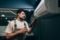 Technician performs maintenance on air conditioning unit while checking data on tablet Royalty Free Stock Photo