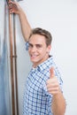 Technician gesturing thumbs up by hot water heater Royalty Free Stock Photo