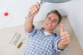 Technician gesturing thumbs up under hot water heater Royalty Free Stock Photo