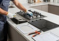 A technician in gloves is installing a new gas hob in a modern kitchen, using tools and a safety checklist to ensure the Royalty Free Stock Photo