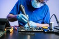 Technician in gloves performs precise soldering on circuit board using hot air gun. Concept of electronics repair Royalty Free Stock Photo