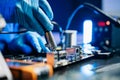 Technician in gloves performs precise soldering on circuit board using hot air gun. Concept of electronics repair Royalty Free Stock Photo