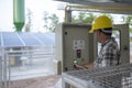 Technician at groundwater pumping station with solar or alternative energy uses a tablet to control and monitor