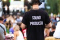 Technician guy in headphones and t-shirt with the inscription sound producer on his back at a outdoor show