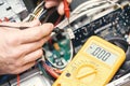 Technician hands with voltmeter above computer motherboard. Repair of computers concept. Toned with selective focus Royalty Free Stock Photo