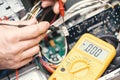 Technician hands with voltmeter above computer motherboard. Repair of computers concept. Toned with selective focus