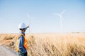 Technician helmet-clad engineer inspects windmill farm