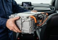 Technician holding electric vehicle battery pack inside modern car. EV power unit with orange cables for installation and Royalty Free Stock Photo