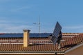 A technician hovering on a red tiled roof lifts a solar panel that he is about to add to a photovoltaic system being installed Royalty Free Stock Photo