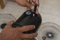A technician inserts or removes the oscillation knob of a dismantled electric stand fan under repair or cleaning