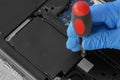 Technician installing hard drive HDD to a laptop computer using screwdriver.
