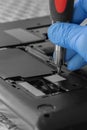 Technician installing hard drive HDD to a laptop computer using screwdriver.