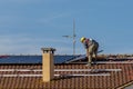 A technician lays the solar panels of a photovoltaic system on top of a red-tiled roof Royalty Free Stock Photo