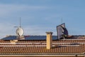 A technician lifts a solar panel as he is installing a photovoltaic system on top of a red-tiled roof Royalty Free Stock Photo