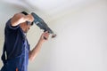 Technician man with hammerdrill installing an air conditioning in a client house, Young repairman fixing air conditioner unit, Royalty Free Stock Photo