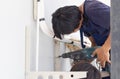 Technician man with hammerdrill installing an air conditioning in a client house, Young repairman fixing air conditioner unit, Royalty Free Stock Photo