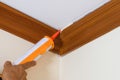 Technician man hand using glue gun or manual caulking gun with polyurethane silicone to repair and fix the wooden cornice with the