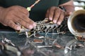 The technician man is repairing the vintage style saxophone instrument.