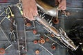 The technician man is repairing the vintage style saxophone instrument.