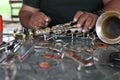 The technician man is repairing the vintage style saxophone instrument.