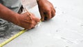 The technician measures the length of the metal plate with a measuring tape and writes the distance with a pencil