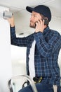 technician on phone fixing cctv camera on wall Royalty Free Stock Photo