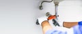 Technician plumber using a wrench to repair a water pipe under the sink. Concept of maintenance, fix water plumbing leaks, replace Royalty Free Stock Photo