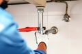 Technician plumber using a wrench to repair a water pipe under the sink. Concept of maintenance, fix water plumbing leaks, replace Royalty Free Stock Photo