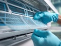 Person wearing blue gloves removing and cleaning a reusable air conditioner filter in a modern indoor cooling unit for maintenance Royalty Free Stock Photo