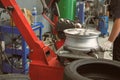 Technician removing rubber from car wheel disc & balancing tyre on balancer in auto repair garage