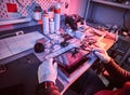 The technician repairs a broken tablet computer in a repair shop. Illumination with red and blue lights Royalty Free Stock Photo