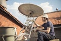 a technician securing a new satellite dish to the roof of a home