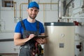 Technician servicing an hot-water heater. Man check equipment of the boiler-house - thermometer. Royalty Free Stock Photo