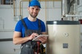 Technician servicing an hot-water heater. Man check equipment of the boiler-house - thermometer. Royalty Free Stock Photo