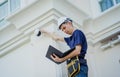 A technician sets up a CCTV camera on the facade of a residential building. Royalty Free Stock Photo