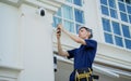 A technician sets up a CCTV camera on the facade of a residential building. Royalty Free Stock Photo