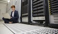 Technician sitting on floor beside server tower using laptop Royalty Free Stock Photo