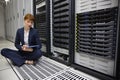 Technician sitting on floor beside server tower using tablet pc Royalty Free Stock Photo