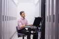 Technician sitting on swivel chair using laptop to diagnose servers