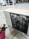 A technician spraying a chemical substance on air conditioner compressor using water dispenser pump.