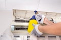 Technician spraying chemical water onto air conditioner grid to