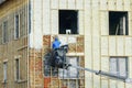 Technician spraying thermal insulation foam layer on the exterior wall using plural component gun for polyurethane foam