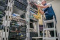 Technician standing on a ladder connects internet wires. The specialist works in the server room of the data center. Worker lays Royalty Free Stock Photo