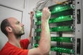 The technician supports the work of a modern data center. A man switches the wires in the computer equipment. Portrait of a Royalty Free Stock Photo