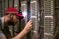 Technician switches the wires to the cross panel in the server room. The specialist shines a flashlight on the IP telephony patch Royalty Free Stock Photo