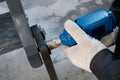 A technician tightens the bolt with an electric tool. Close-up of male hands tightening a nut on a metal product. Gun for twisting